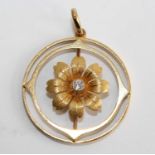 A yellow metal circular openwork floral pendant, having a round brilliant cut diamond millegrain set