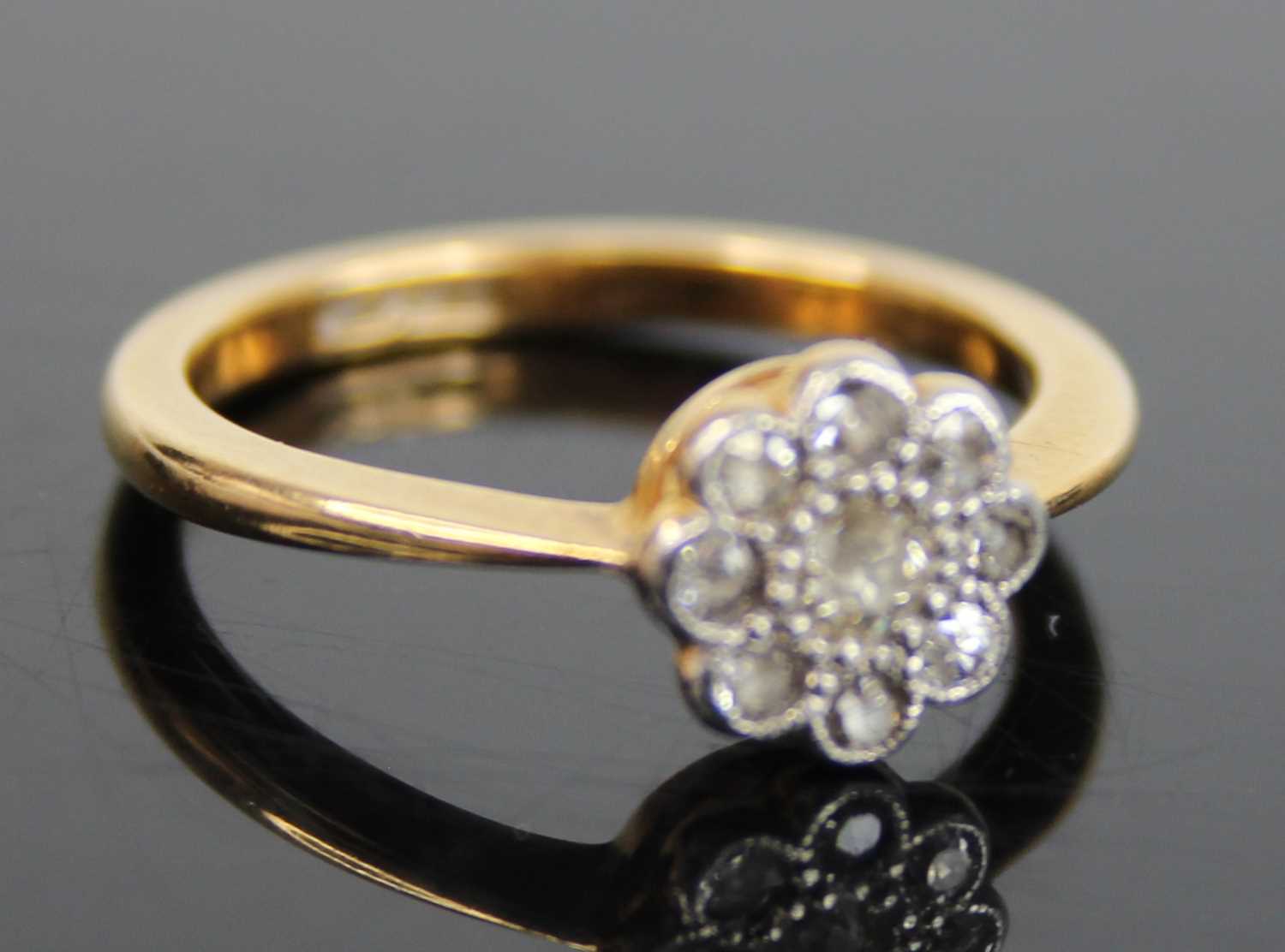 An 18ct gold diamond flower head cluster ring, arranged as a centre round cut within a surround of