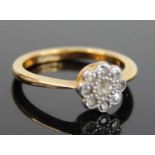 An 18ct gold diamond flower head cluster ring, arranged as a centre round cut within a surround of