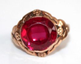A yellow metal and synthetic ruby set dress ring, the large round cut red stone measuring approx