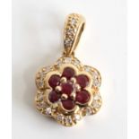 A yellow metal, ruby and diamond flower cluster pendant, featuring seven round rubies to the centre,