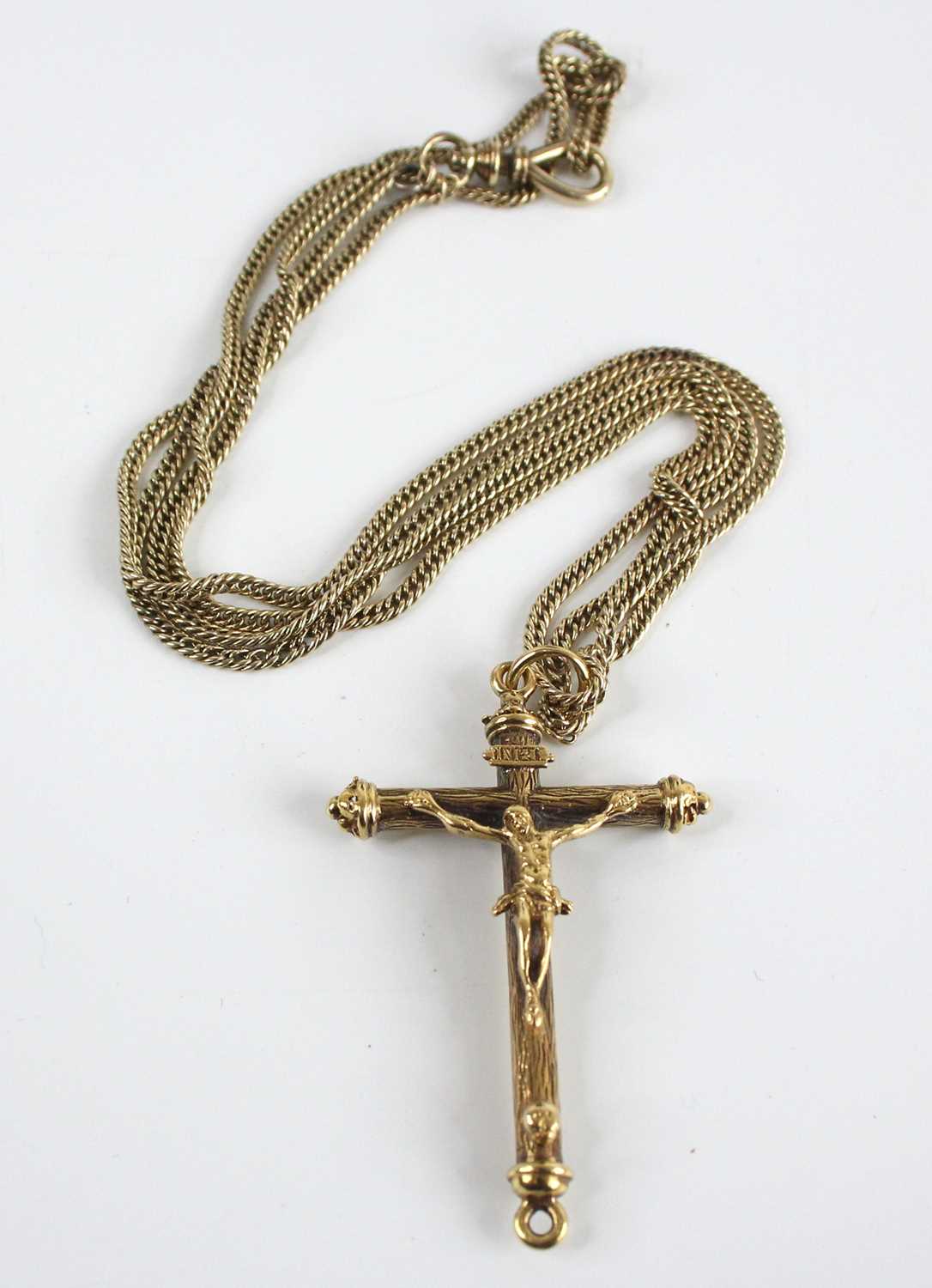 A yellow metal ornate crucifix attached to a curb link long guard chain, with swivel clasp, crucifix