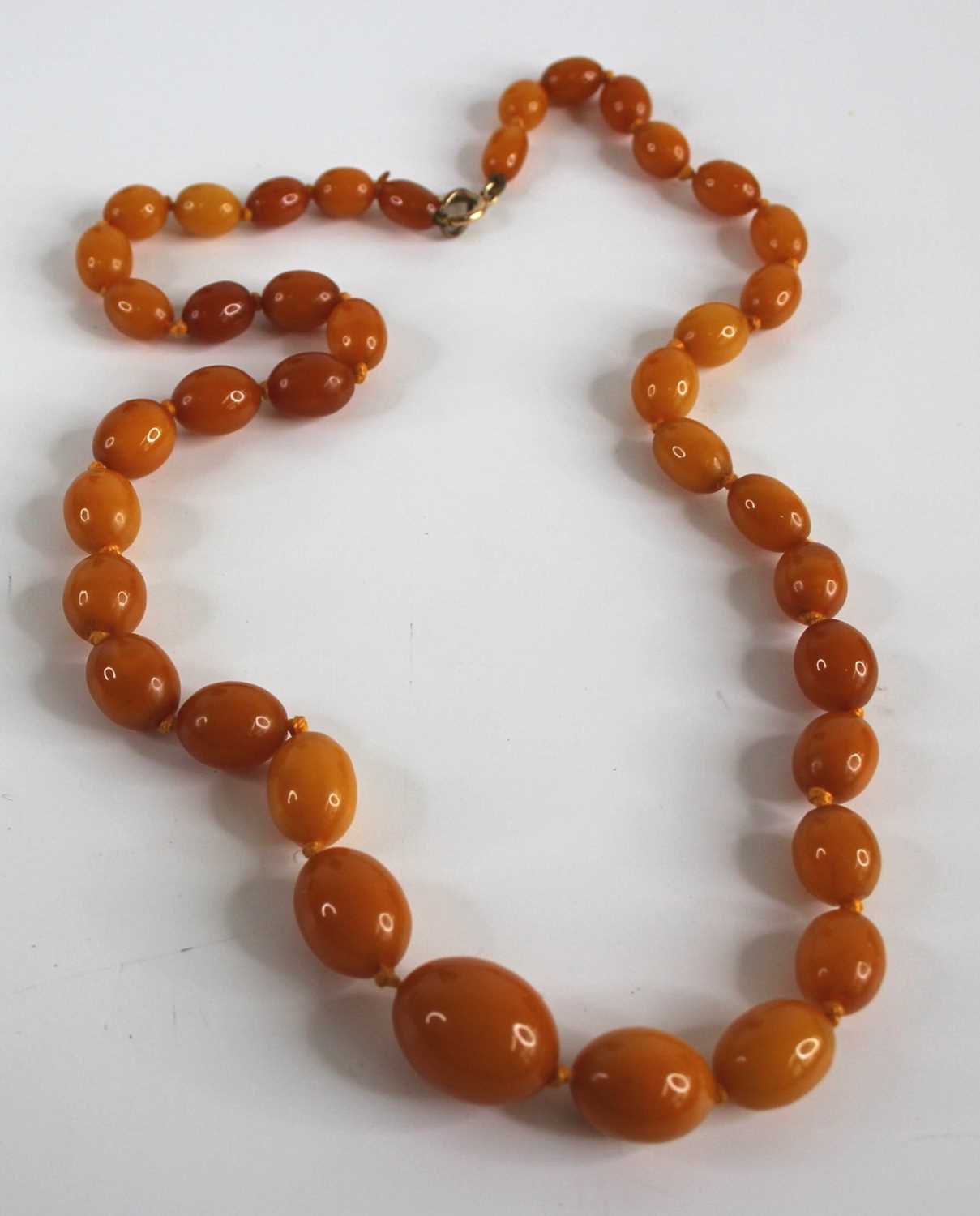 A beaded butterscotch amber single string necklace, arranged as 39 graduated barrel beads on a - Image 2 of 2