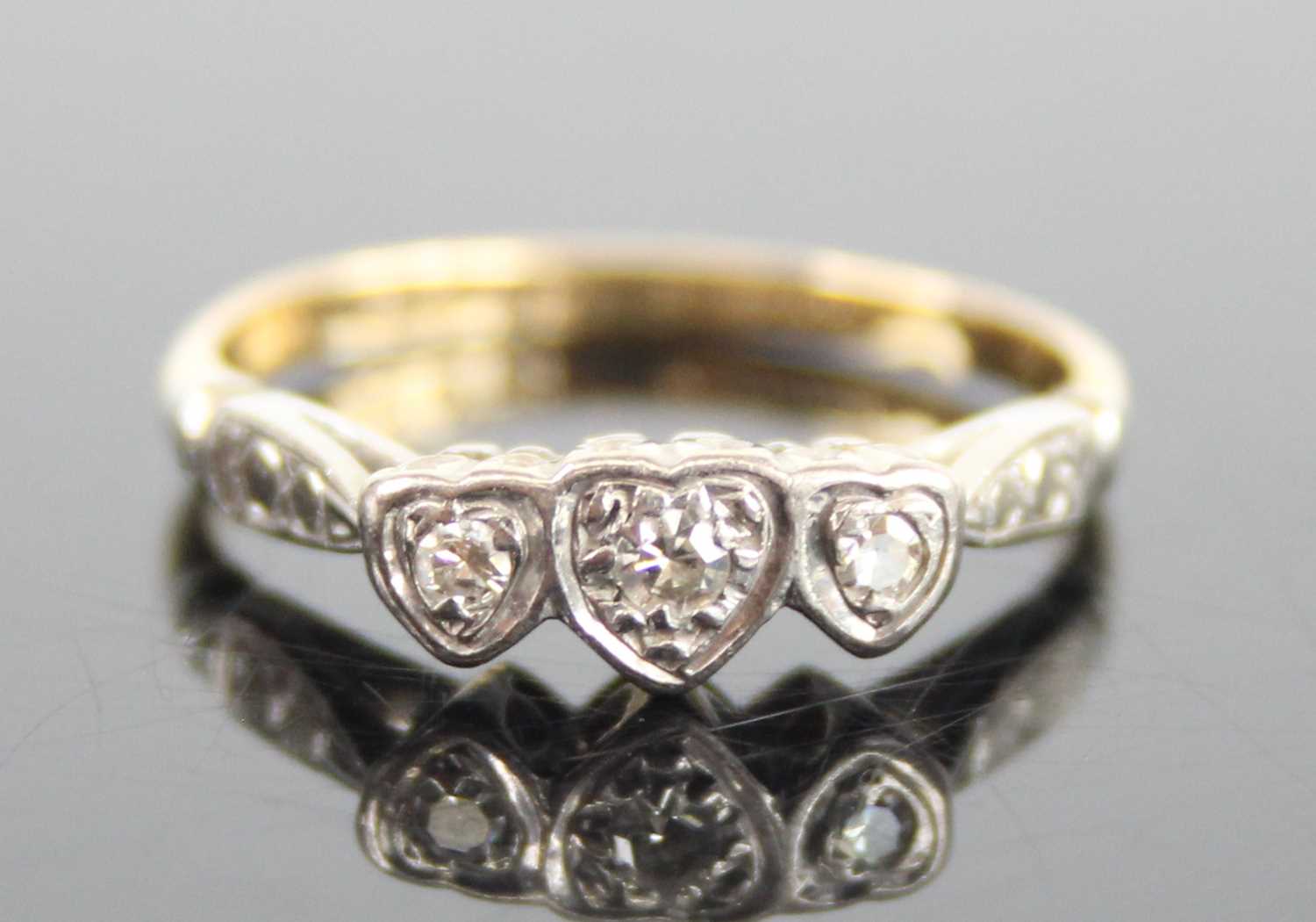 A yellow and white metal diamond three-stone ring, having three single cut diamond in heart shaped