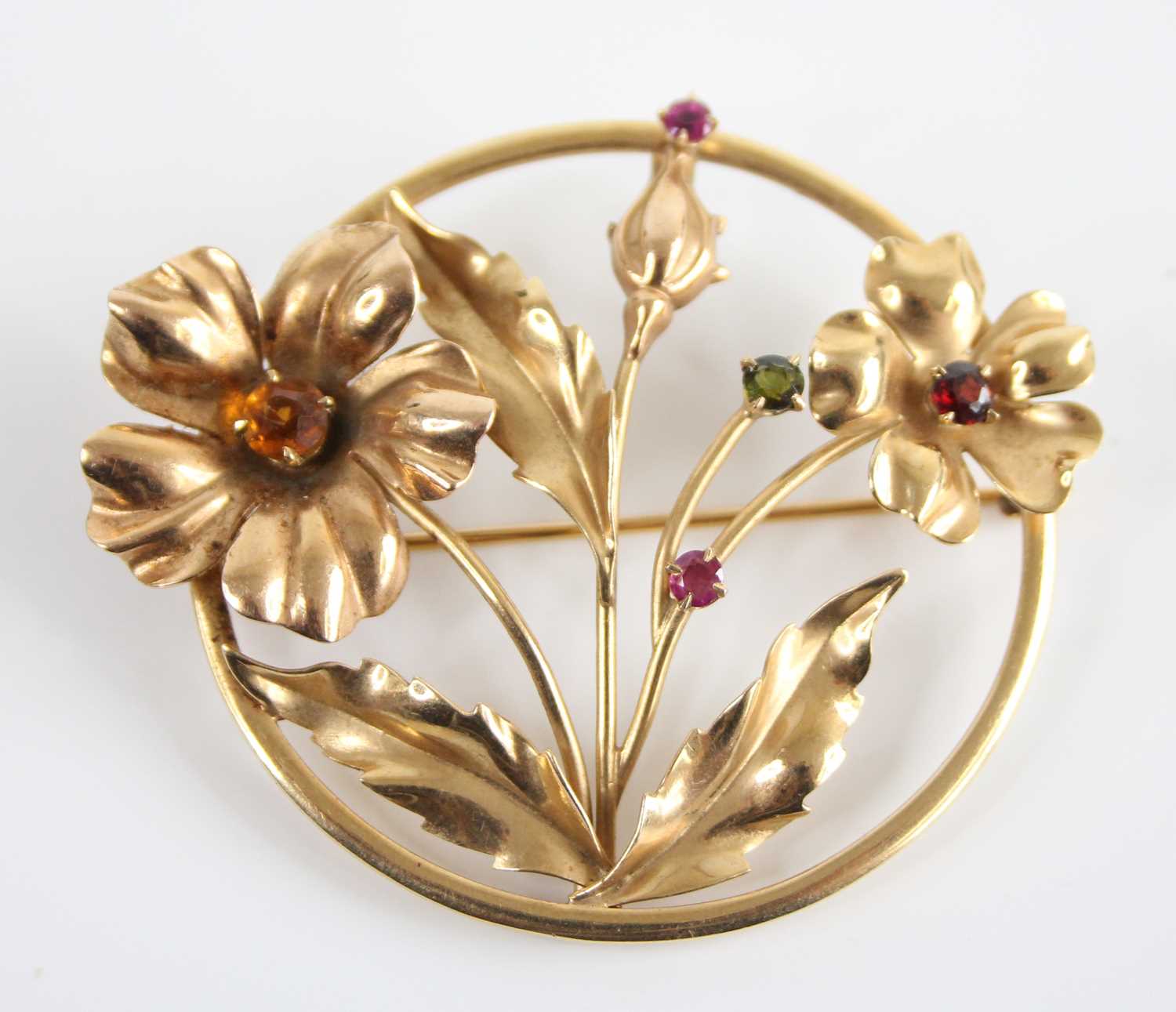 A yellow metal multi-stone openwork floral circular brooch, set with citrine, peridot, garnet and