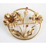A yellow metal multi-stone openwork floral circular brooch, set with citrine, peridot, garnet and