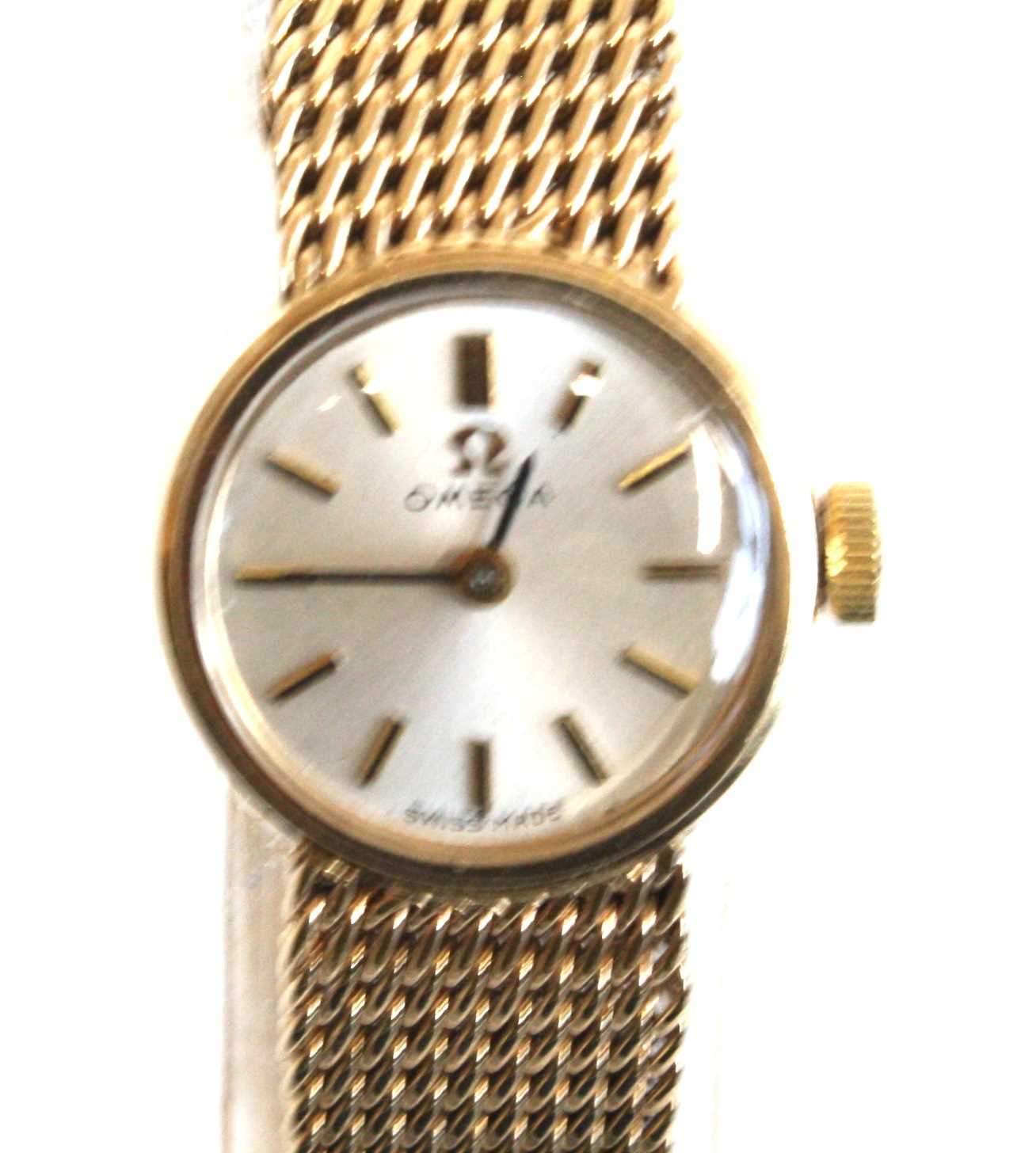 A lady's 9ct yellow gold Omega manual wind wristwatch with round silver baton dial and integral