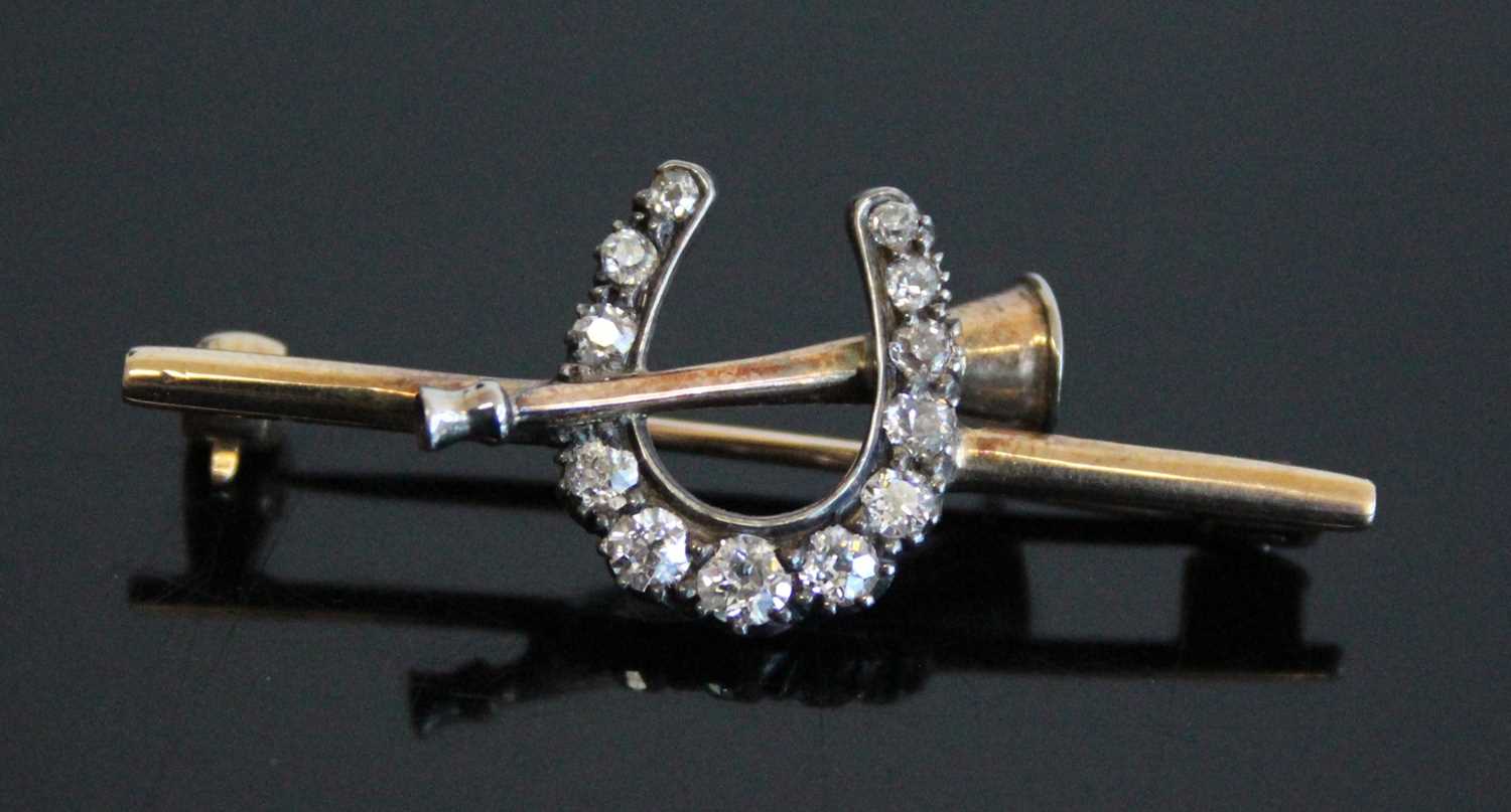 A circa 1900 yellow metal diamond set hunting brooch, arranged as a horseshoe and post-hunt horn,