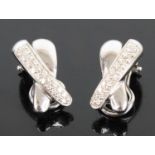 A pair of 18ct white gold diamond two-strand crossover clip earrings, each comprising a strand of 21