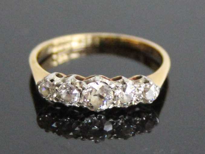 A yellow and white metal diamond half eternity ring, comprising five graduated Old European cut
