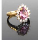 A yellow metal pink sapphire and moissanite set dress ring, the pear cut four claw set sapphire