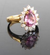 A yellow metal pink sapphire and moissanite set dress ring, the pear cut four claw set sapphire