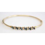 A modern 9ct hollow gold, sapphire and diamond set hinged bangle, arranged as six marquise cut and