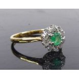 A yellow and white metal, emerald and diamond circular cluster ring, featuring a centre oval emerald