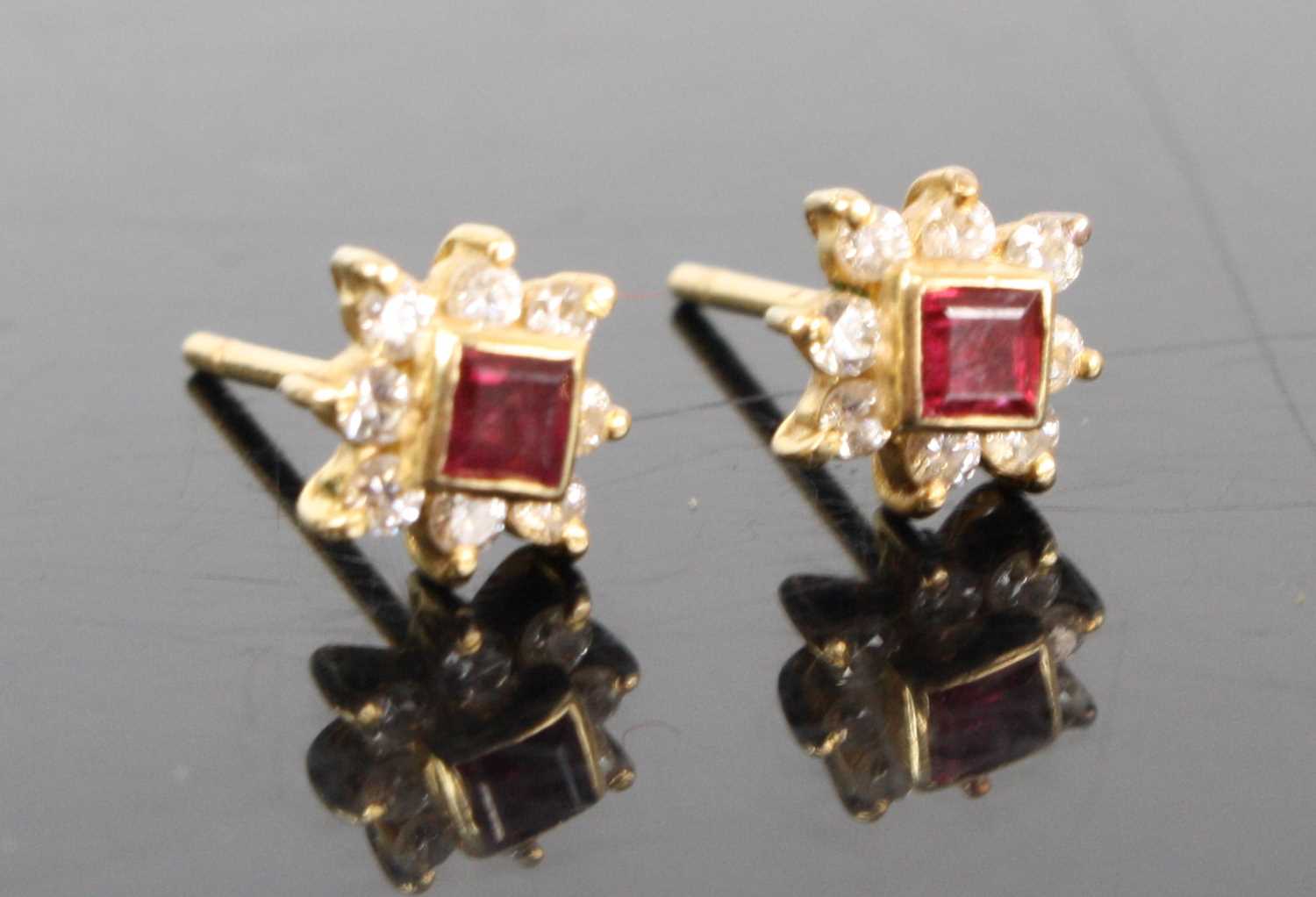 A pair of yellow metal ruby and white stone set flowerhead ear studs, the square cut rubies