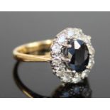 A yellow and white metal, sapphire and diamond oval cluster ring, the centre sapphire within a