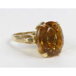 A yellow metal citrine single stone ring, featuring an oval citrine in a four-claw setting with