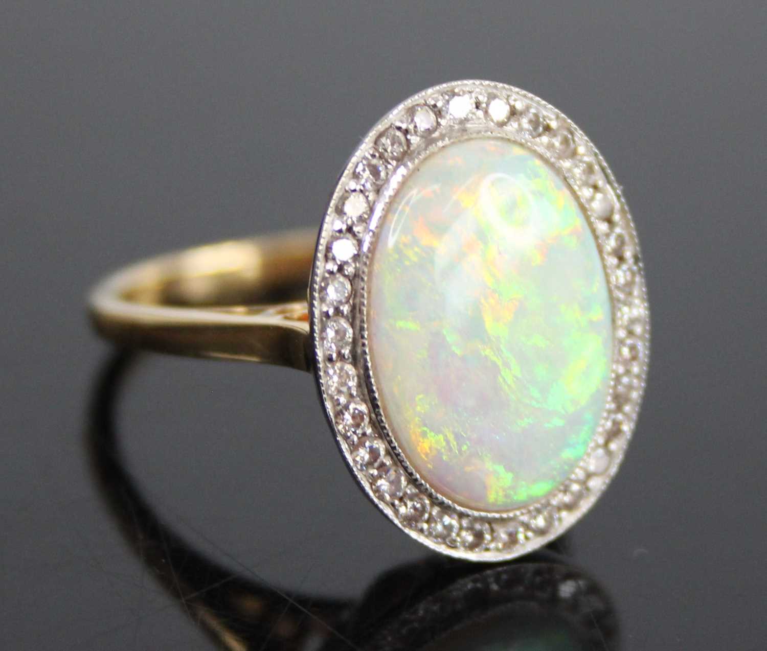 An 18ct yellow and white gold, opal doublet and diamond oval cluster ring, the opal doublet