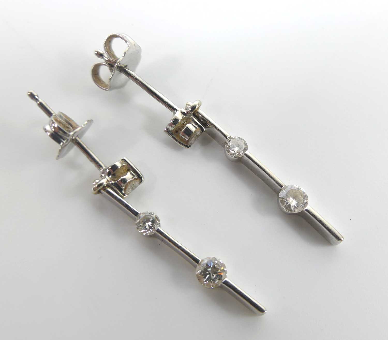 A pair of 18ct white gold diamond bar drop earrings, each with three graduated round brilliant cut