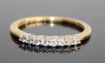 A modern 18ct gold diamond half hoop ring, arranged as eight caw set round brilliants in a line