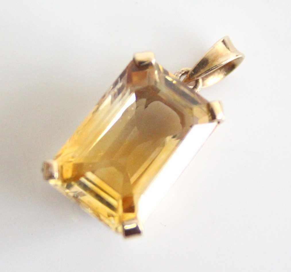 A yellow metal citrine pendant, featuring a rectangular cut citrine in a four-claw setting,