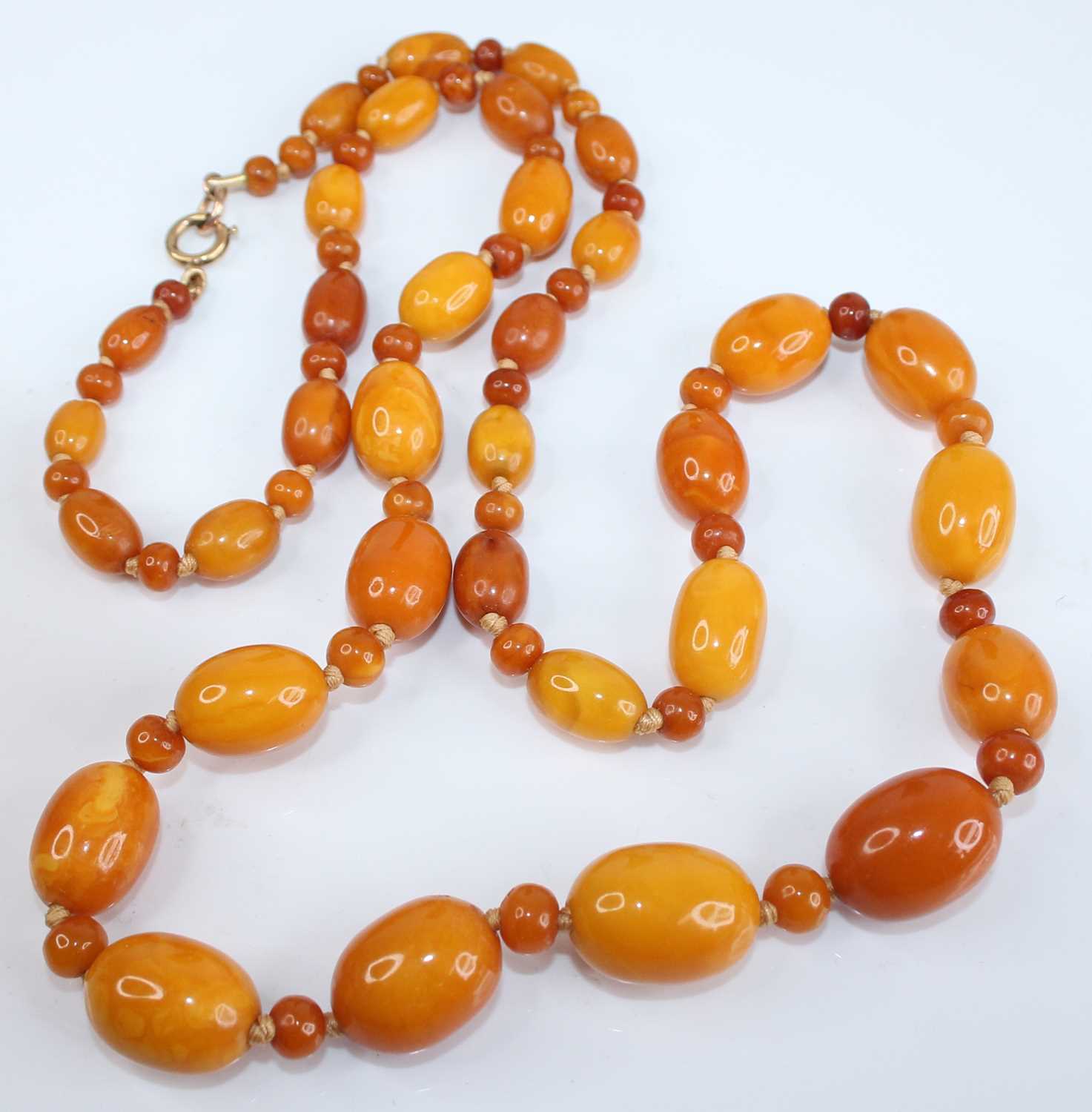 A butterscotch amber necklace, arranged as graduated barrel beads on a knotted string, each with - Image 2 of 3