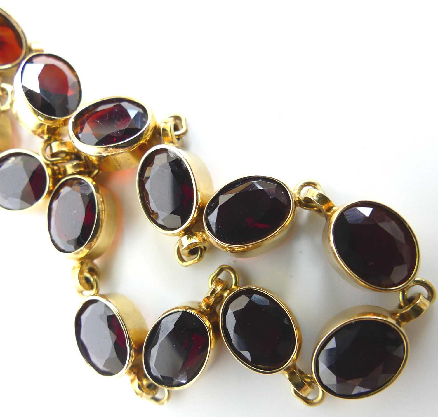 A 9ct yellow gold garnet bracelet, comprising 13 oval almandine garnets in bezel settings, with bolt - Image 3 of 4