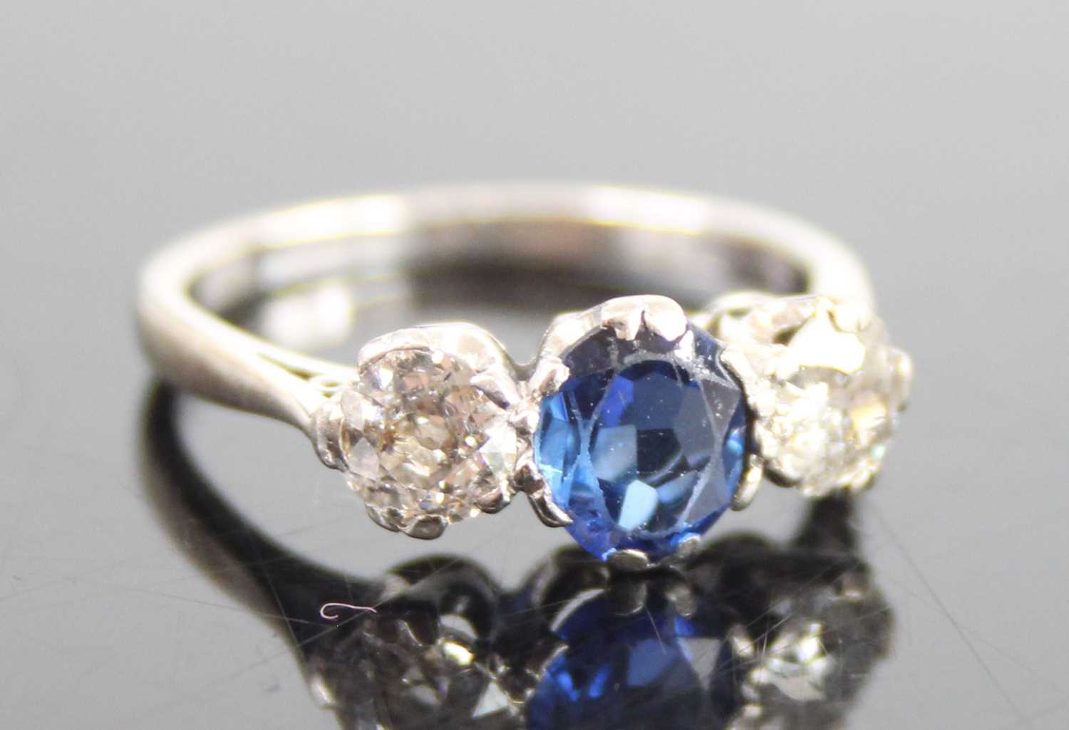 A white metal, sapphire and diamond three-stone ring, featuring a centre oval sapphire with an Old