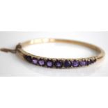 A yellow metal, amethyst and diamond point set hinged bangle, arranged as eleven graduated round cut