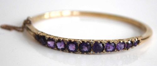 A yellow metal, amethyst and diamond point set hinged bangle, arranged as eleven graduated round cut