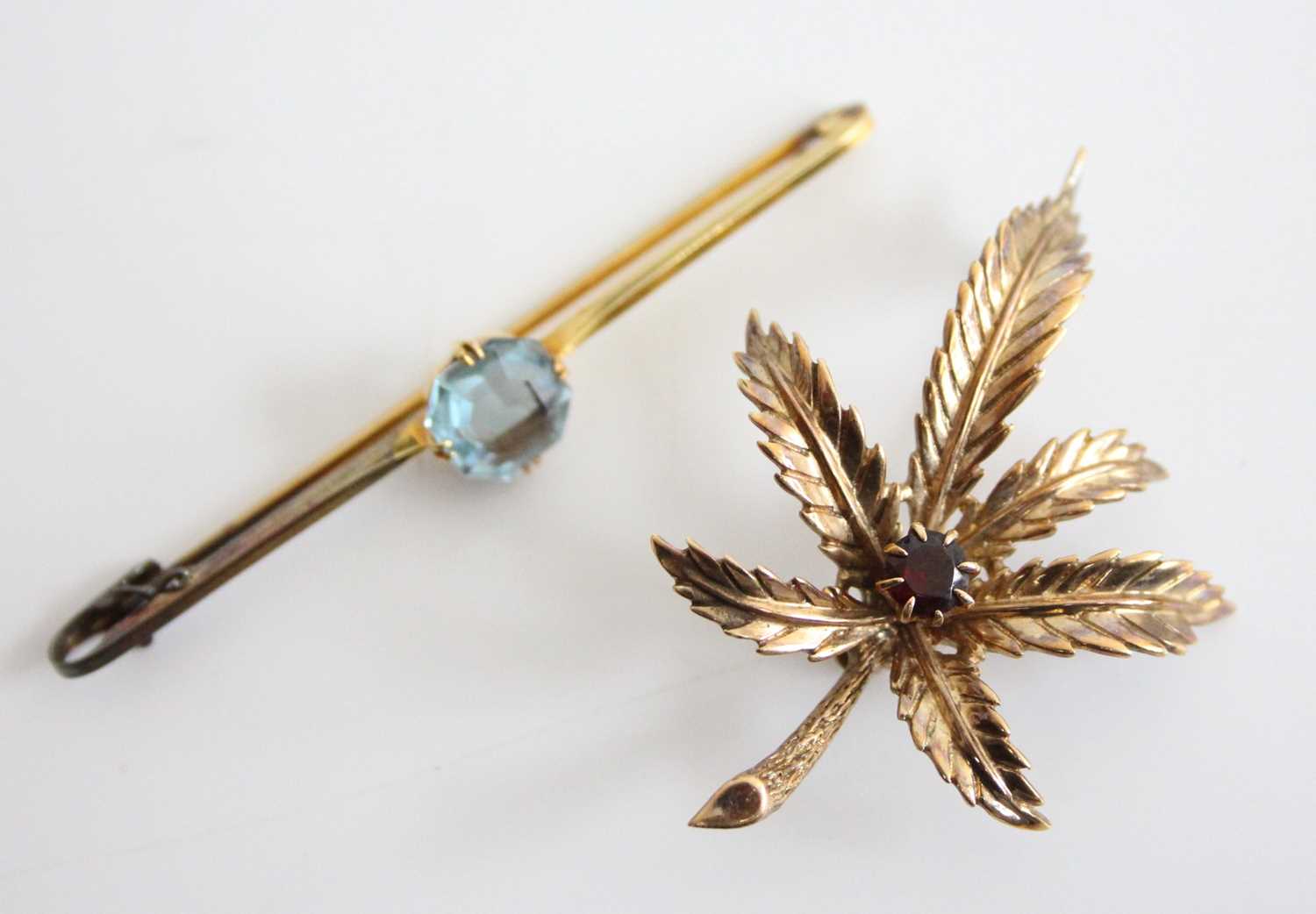 A modern 9ct gold and garnet set fern leaf brooch, the round cut garnet weighing approx 0.3