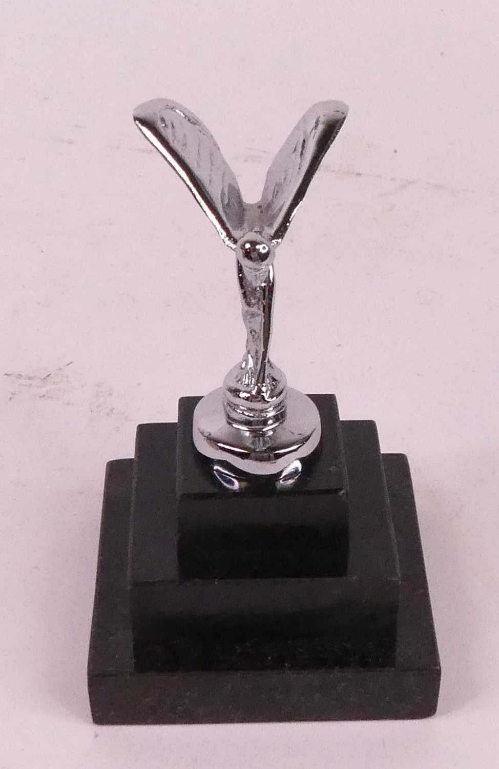 A miniature model of The Spirit of Ecstasy, mounted upon a stepped polished hardstone plinth, h.