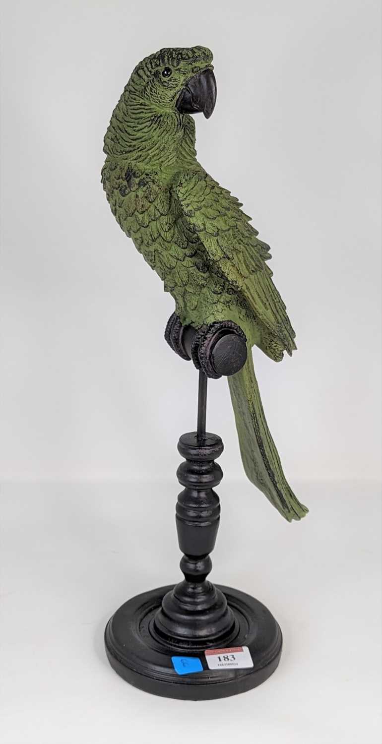 A green painted composite model of a parrot on a perch, height 43cm