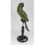 A green painted composite model of a parrot on a perch, height 43cm