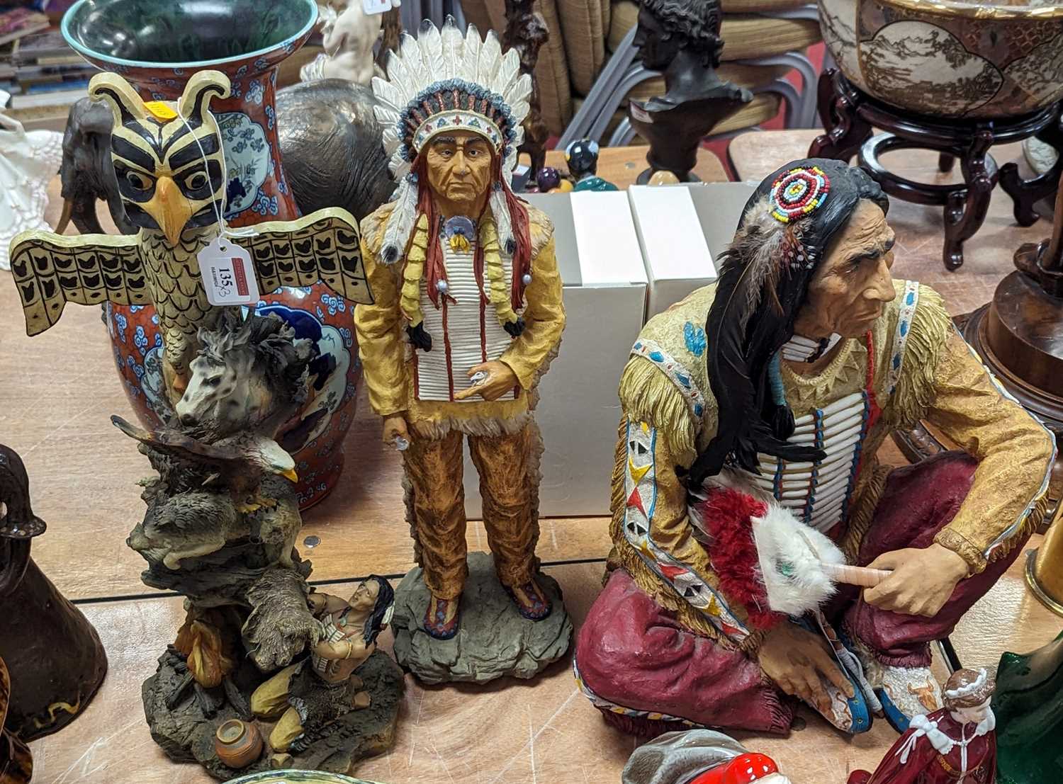 A modern resin figure of a native American man, shown seated, height 44cm, together with two