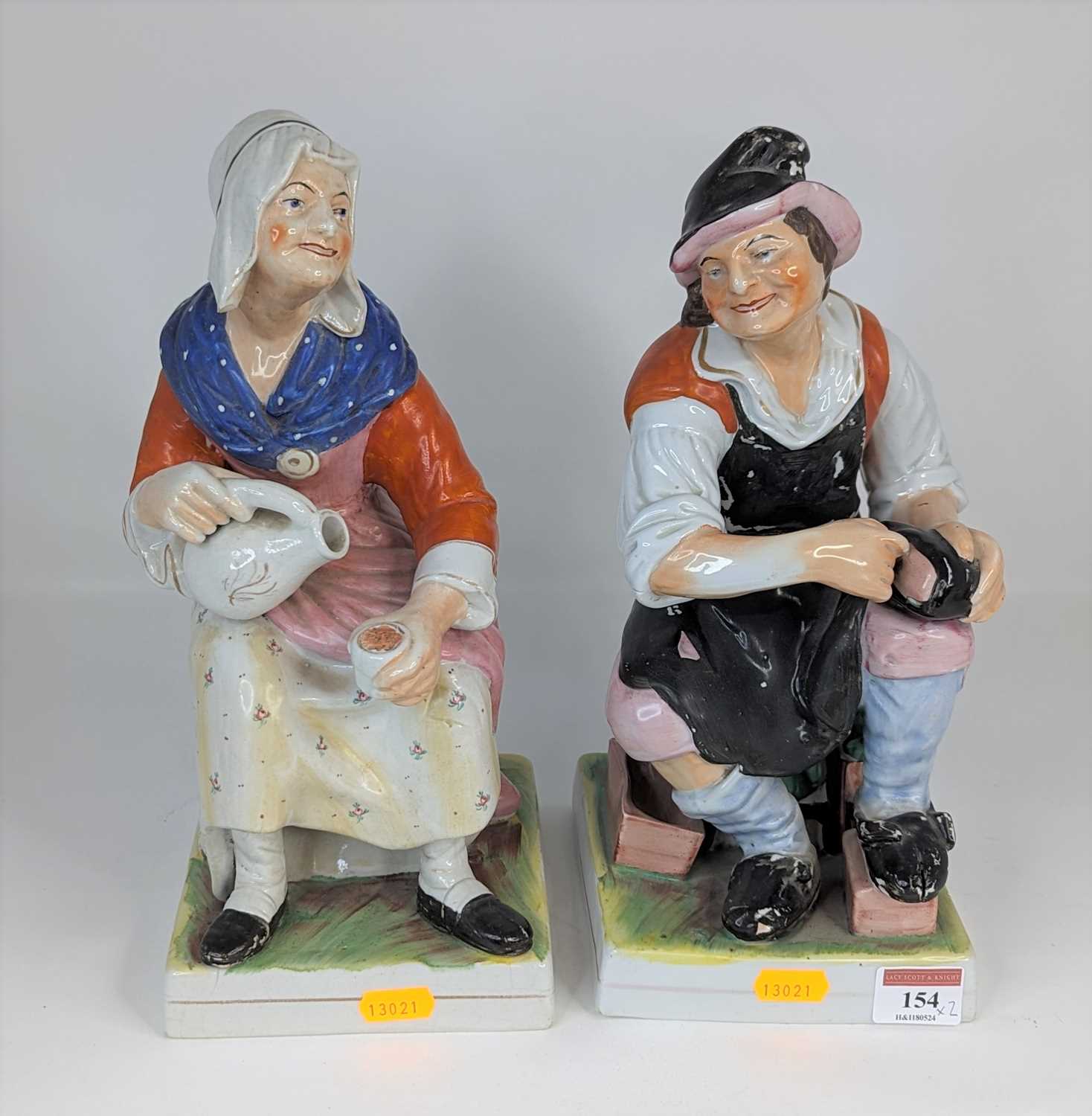 A pair of Staffordshire pottery figures of cobblers, each shown in seated pose, height 31cm