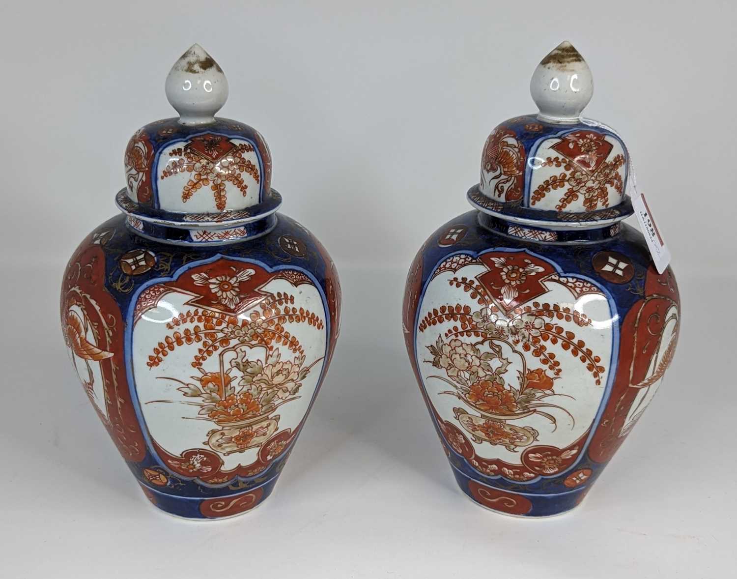 A pair of Japanese Imari jars and covers, each decorated with flowers, height 23cm