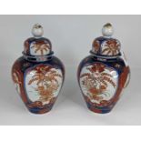 A pair of Japanese Imari jars and covers, each decorated with flowers, height 23cm
