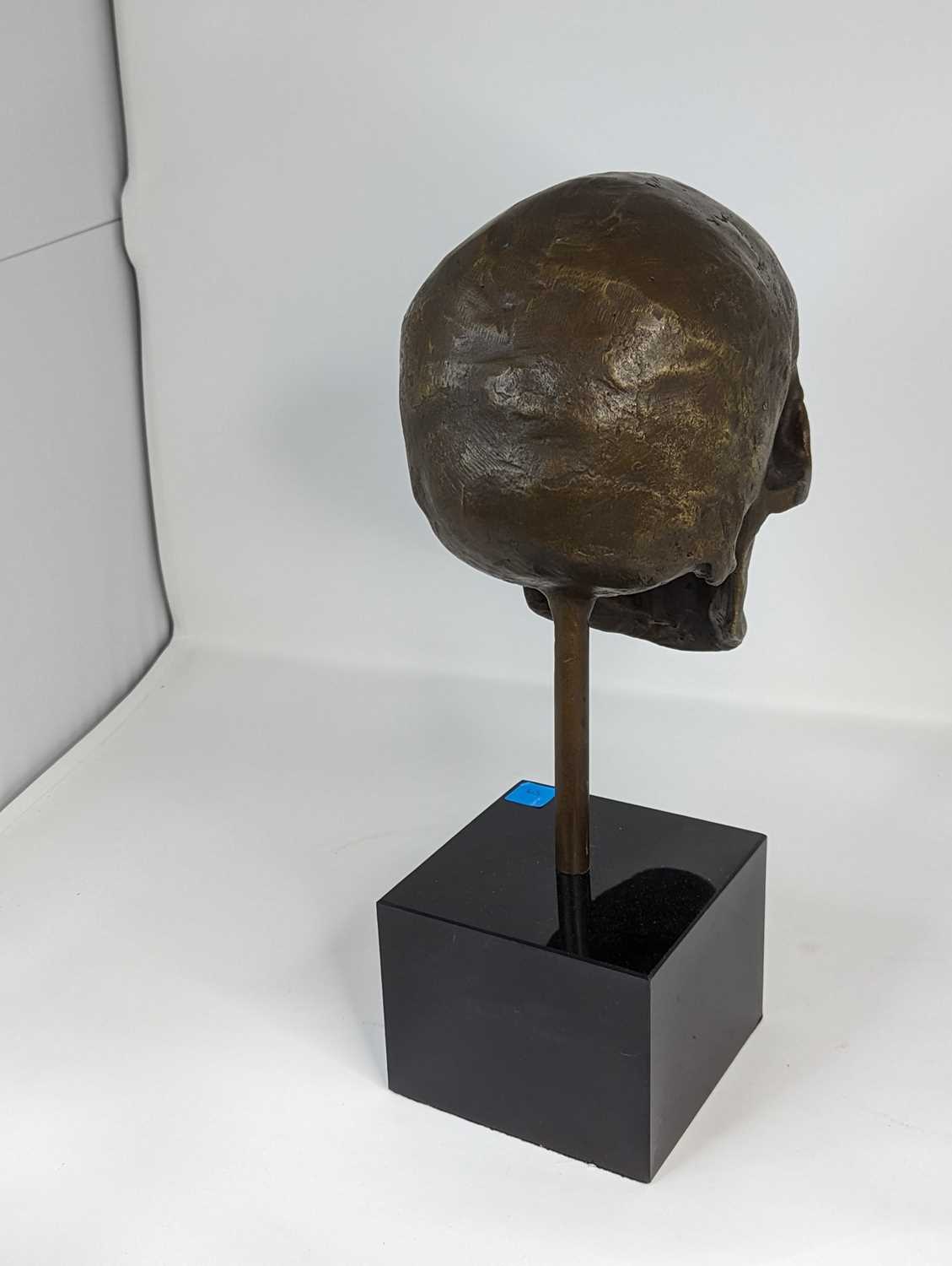 A bronzed metal model of a skull, mounted upon a polished black hardstone plinth, height 35cm - Image 2 of 2