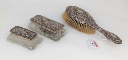 A Victorian silver backed hairbrush having a repoussee C-scrolling decoration together with two