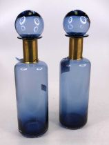 A pair of blue glass bottles, each having a brass collar, height 41cm