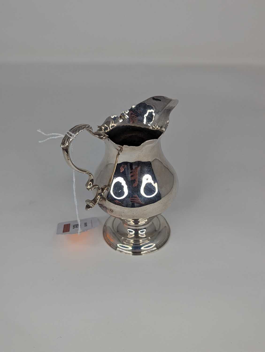 An 18th century silver cream jug of helmet shape having a everted rim, flying C-scroll handle on - Image 2 of 2