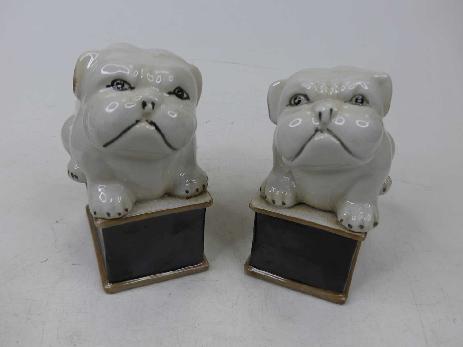A pair of porcelain figures of bulldogs, each shown seated on a plinth, height 15cm