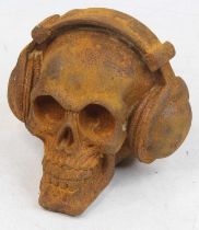 A rusted metal model of a skull wearing headphones, h.12cm
