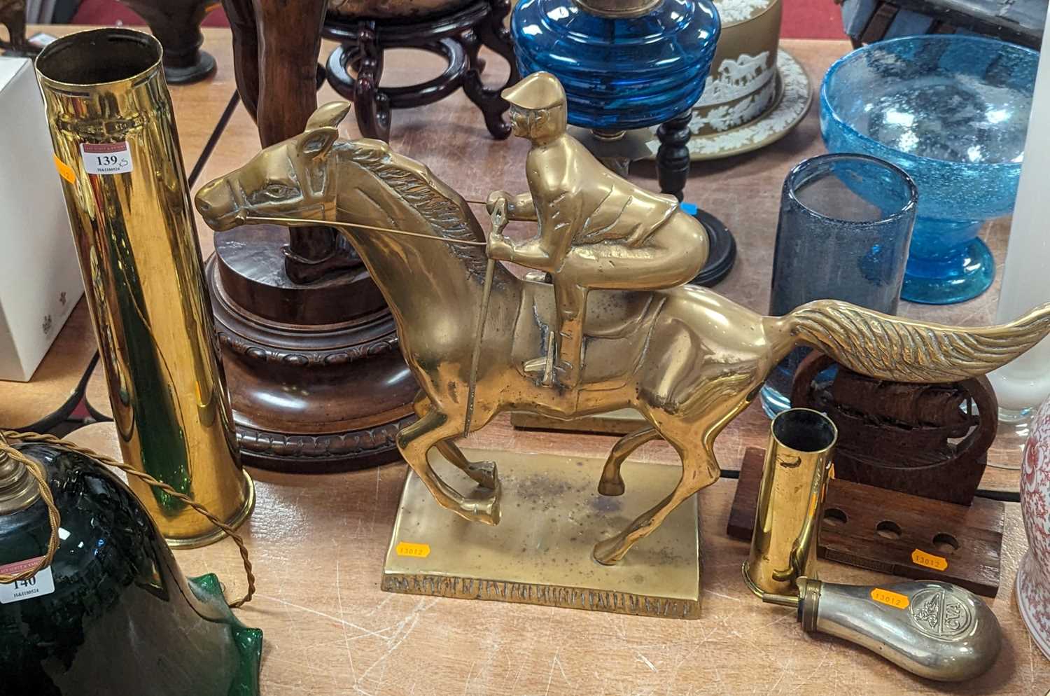 A brass model of a horse & jockey, height 41cm, together with two brass shell cases, a powder