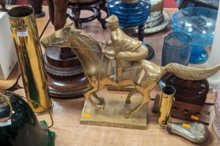 A brass model of a horse & jockey, height 41cm, together with two brass shell cases, a powder