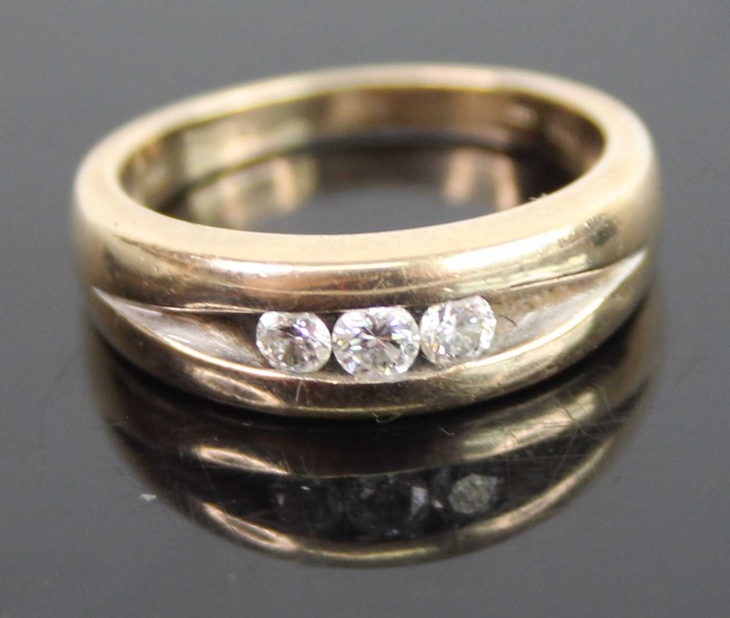 A modern 9ct gold diamond trilogy ring, the flush-set round brilliants having a stated weight of 0.