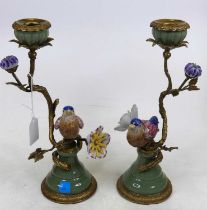 A pair of brass and porcelain table candlesticks in the form of a bird perched upon flowers,