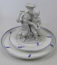 A Meissen blanc de chine porcelain candlestick, in the form of a seated putti before a tree trunk,