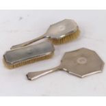 A George V silver backed dressing table set comprising hairbrush, hand mirror, and clothes brush,